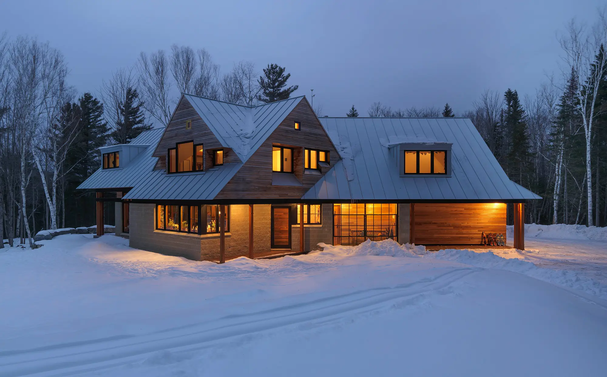 the house in the winter with warm lights and standing seam roof